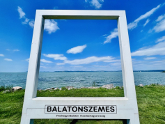 Fényképkeretn keresztülkészített kép: Fehér színű négyzet, amelyen keresztül a kék ég és Balaton úgy látszik mintha egy fénykép volna.